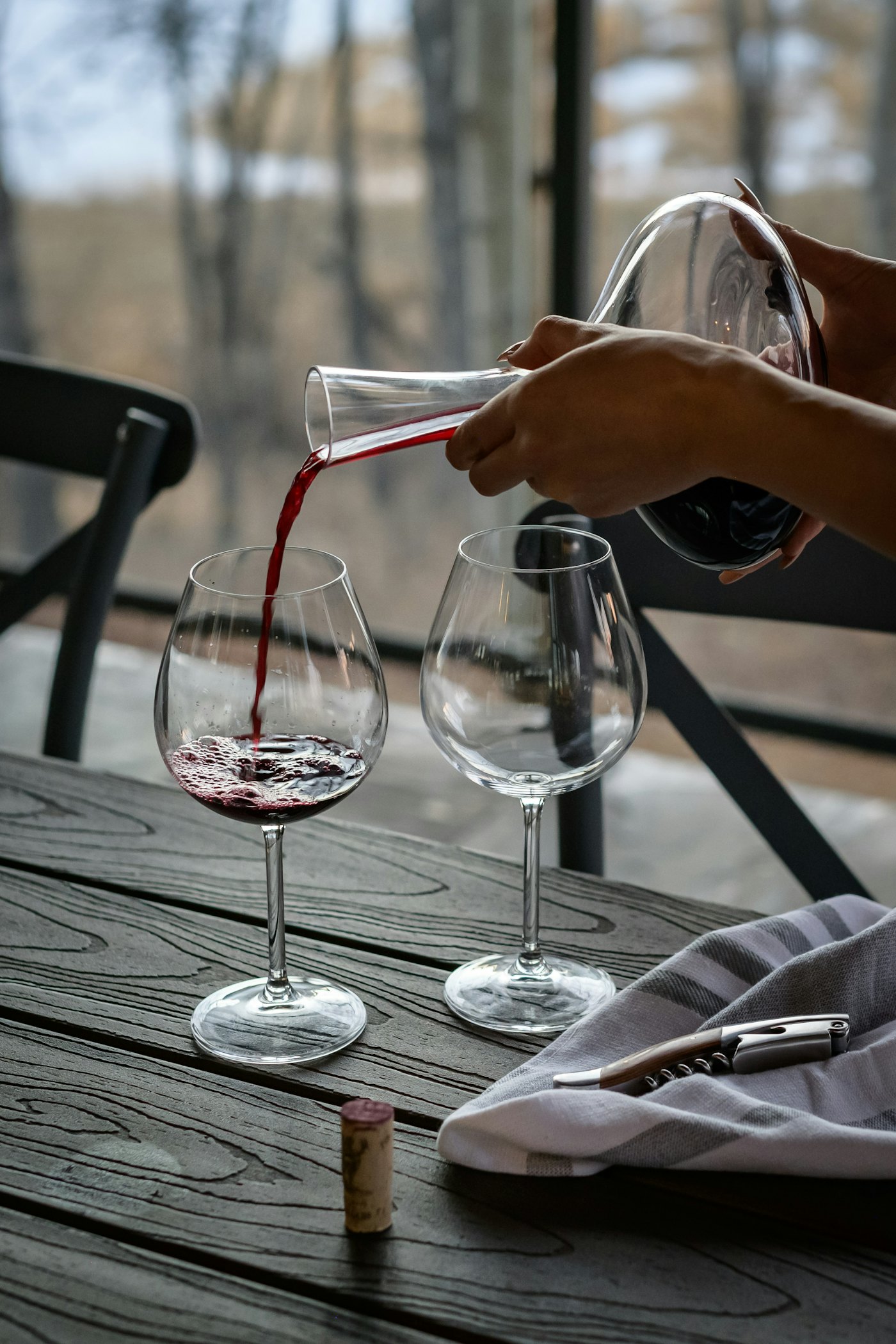 Estate wine decanted into two glasses on a weathered terrace table by the vineyard